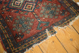 Tattered hand-knotted end with splits, revealing cherry red, blue, and gold geometric guls.