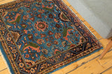 Corner of a fine vintage Engelas rug showing expressive floral vinery and a classic indigo blue border.