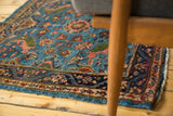 Styled in-home view of a vintage Persian rug's sky blue floral field and indigo border.