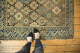 Antique Caucasian rug featuring allover starburst motifs and abstract animals, bordered by deep blue geometrics.