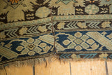Antique Caucasian rug's geometric motifs and indigo border, highlighting an older split.