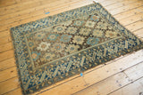 Teal blue and pale bronze geometric border with worn knot heads on an antique Caucasian rug.