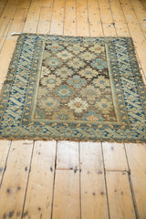 Frayed end of antique Caucasian rug, with geometric borders in teal, oxidized green, and ivory.