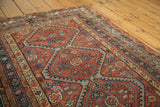 Scalloped indigo motifs and germinating floral designs on antique Mission Malayer rug's terra cotta field.