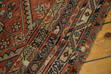 Patched area and wear on the antique Malayer rug, with terra cotta and indigo geometric motifs.