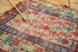 Close-up of geometric stylized germinating flowers on vintage Caucasian rug, showing even wear.