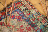 Fringed edge of a vintage Caucasian rug, displaying geometric stylized flowers in vivid colors.