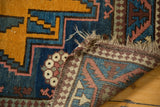 Hand-knotted vintage Russian runner showing folded edge, tattered fringe, and traditional geometric patterns.