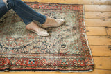 Vintage Dargezine rug shows faded brick red and navy floral patterns, heavy wear, and tattered right edge.