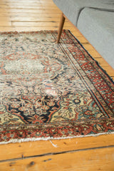 Tattered fringe and worn floral field of a Dargezine rug with brick red, navy, beige tones.