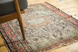 Angled close-up of a Dargezine rug, revealing worn floral motifs and a tattered brick red border.