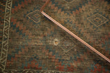 Vintage Belouch rug: dark field, serrated gul pattern, and hole exposing foundation.