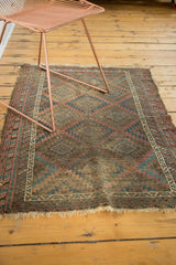 Worn texture of the vintage Belouch rug with serrated gul motifs and tattered fringe.