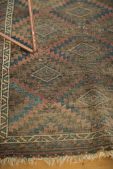 Vintage Belouch rug detail showing geometric gul panels, worn border, and tattered fringe.