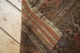 Antique Belouch rug's fringed edge, showing hard tatter and weave in madder red, brown hues.
