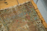 Vintage Oushak rug corner, showing tattered fringe, hook-and-latch motifs, dusty gold, and apricot tones.