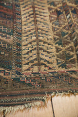 Antique Belouch rug close-up with worn tribal pattern, visible knot heads, and tattered end.