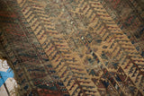 Worn antique Belouch rug pile with visible knot heads, barber pole border, and tattered edge.