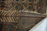 Folded antique Belouch rug edge showing tattered fringe and detailed hand-knotted foundation.