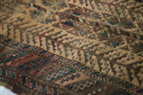 Detail of antique Belouch rug showing textured wear, visible knot heads, and camel, red, blue tones.