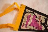 Stitched yellow felt hoist and ties on a vintage black souvenir pennant.