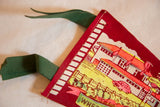 Green felt ties and white stitched border on a vintage red pennant, showing minor pinholes.