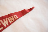 Vintage red felt flag detail with cream 'WIND' text and textural wear.