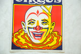 Bold graphic detail of the happy clown's face in vibrant red, yellow, and blue.