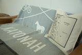 Katonah NY map pillow resting on a wooden bench with a grey Katonah graphic throw.
