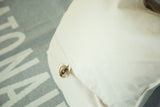Brown marbled button on the envelope closure of the cream cotton Katonah map pillow.