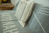Off-white cotton fabric texture and crisp stitched corner of the map pillow.