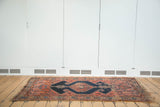 Full view of antique Malayer rug: navy diamond medallion, ornate vinery on faded brick.