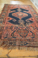 Tattered fringe and faded brick red vinery on an antique Malayer rug.
