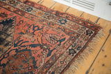 Antique Malayer rug corner with hard tatter fringe, faded brick field, and navy motifs.