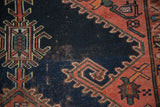 Patinaed navy blue field of an antique Malayer rug featuring geometric stylized rams horn motifs.