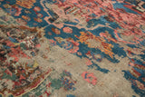 Exposed foundation on antique Karabagh Soumac rug with faded blue, red, and yellow floral patterns.