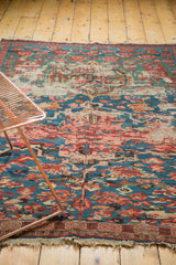 Worn edge of antique Karabagh Soumac rug, revealing tattered fringe and blue-red wave border pattern.