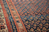 Close-up of antique hand-knotted Kurdish Malayer runner, repeating madder red boteh, indigo blue, geometric borders.