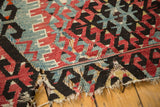 Antique Turkish Kilim with large hole, tattered edge, and geometric motif in cherry red, blue, black.