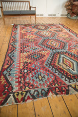 Tattered end of antique Turkish Kilim carpet, with geometric red, blue, and black motifs.