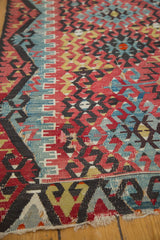 Antique Turkish Kilim corner featuring geometric patterns in cherry red, faded blue, and gold with aged wear.