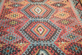 Antique Turkish Kilim: charcoal hook and latch motifs, cherry red, sky blue, and aged, threadbare texture.