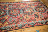 Antique Kilim flatweave's geometric hook-and-latch pattern in cherry red, blue, gold; aged edge.