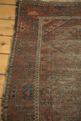 Antique Belouch rug side border with madder red geometric motifs and wear revealing knot heads.