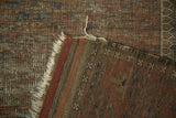 Hand-knotted reverse, tattered fringe, and worn pile texture of an antique Belouch rug.