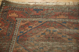 Antique Belouch rug: geometric madder root red and navy patterns with visible knot head wear.