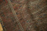 Antique Persian Belouch rug, worn pile and exposed foundation with madder red and brown patterns.