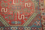 Close-up of cherry red, sky blue, ivory geometric patterns, exposed foundation wear.