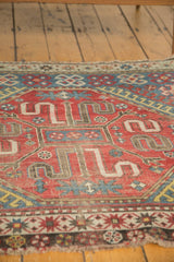 A Caucasian vintage rug corner, revealing tattered fringe and geometric motifs.