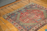 Hard tattered fringe and geometric cherry red and sky blue patterns on a vintage Caucasian rug corner.